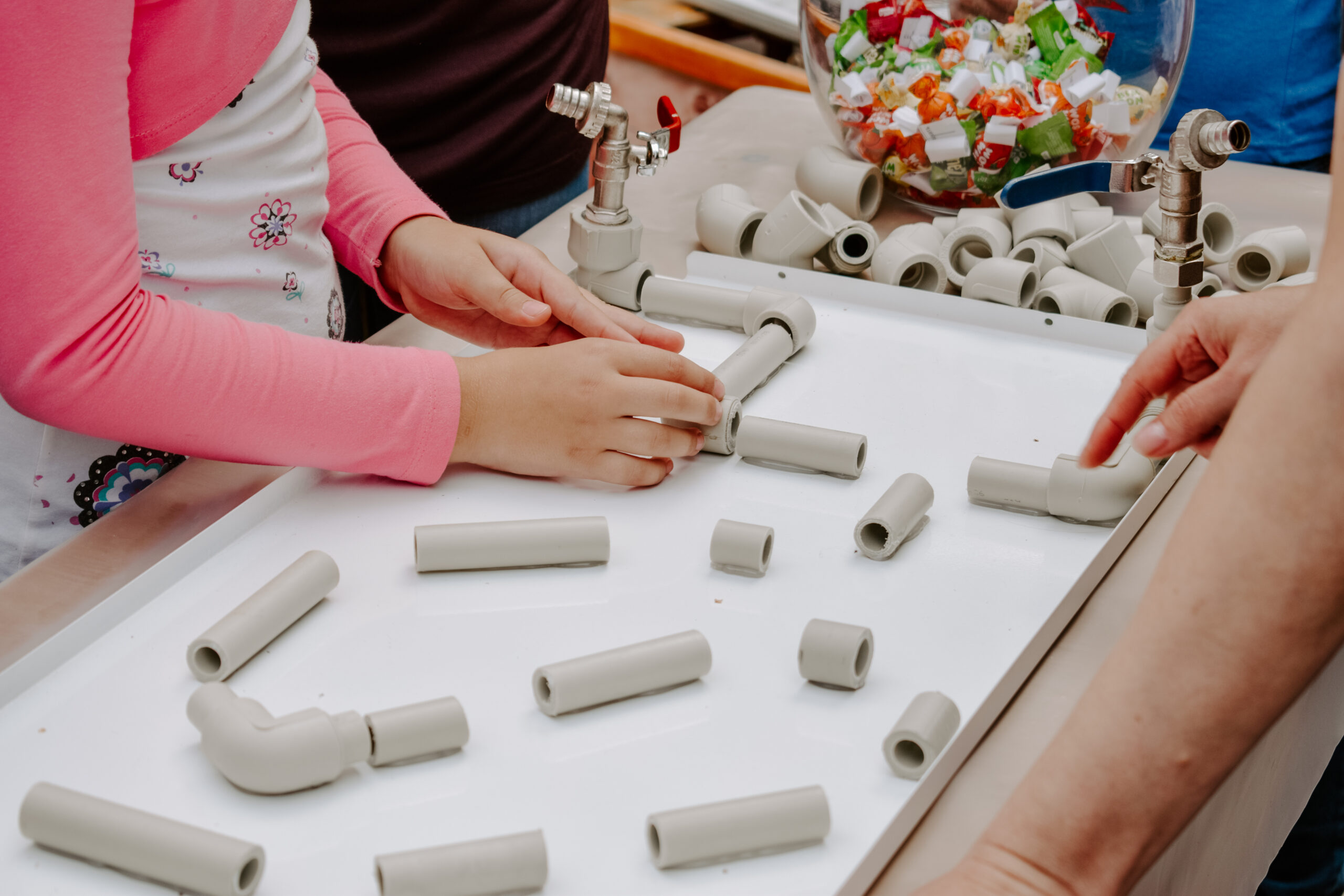 Activity for kids indoor, play and creativity concept. Kids are playing with fun tunnels and pipes set, plastic block kit. Fun-filled waterway pipe builders for create twisting turning constructions